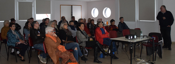 Pierre Deligniere standing at the back and on the right of the photo, 
					telling whisky stories to the public, about thirty persons sitting on the left, listening attentively to the contributor.