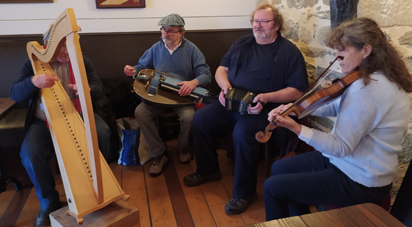 Photo of the group Dz Eire, Fañch on harp, Jean-Pierre on hurdy-gurdy, Jakez on accordion and Annaïg on violin.