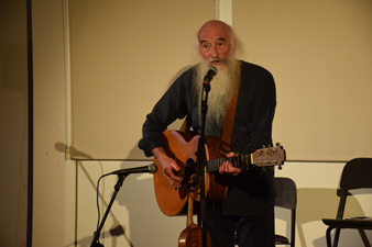 Photo of Patrick Ewen playing guitar and singing into the microphone